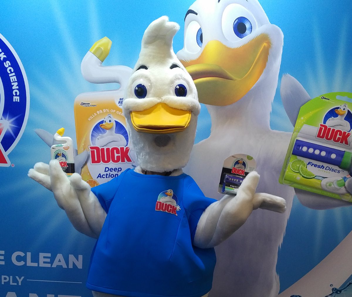 A mascot character performer posing with a product during a trade show