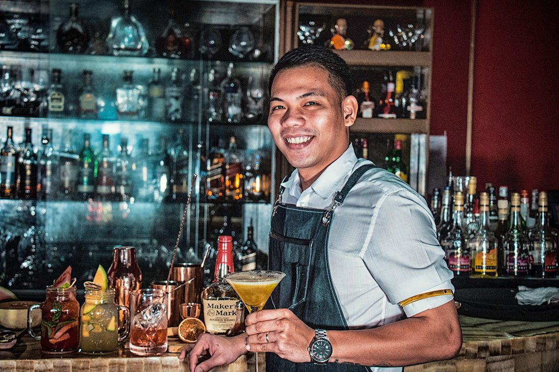 A smiling bartender holding a cocktail