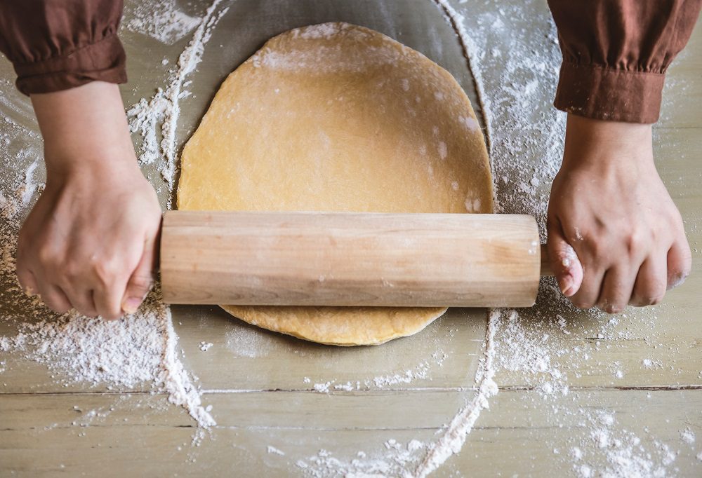 kitchen hand rolling dough
