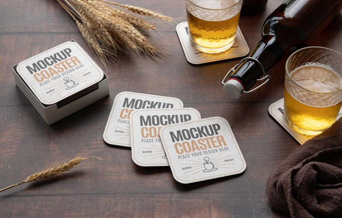 Beer coasters laid across a table with two supporting beer glasses